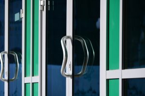 Chrome door handle and glass of modern aluminium double-glazed office door facade detail
