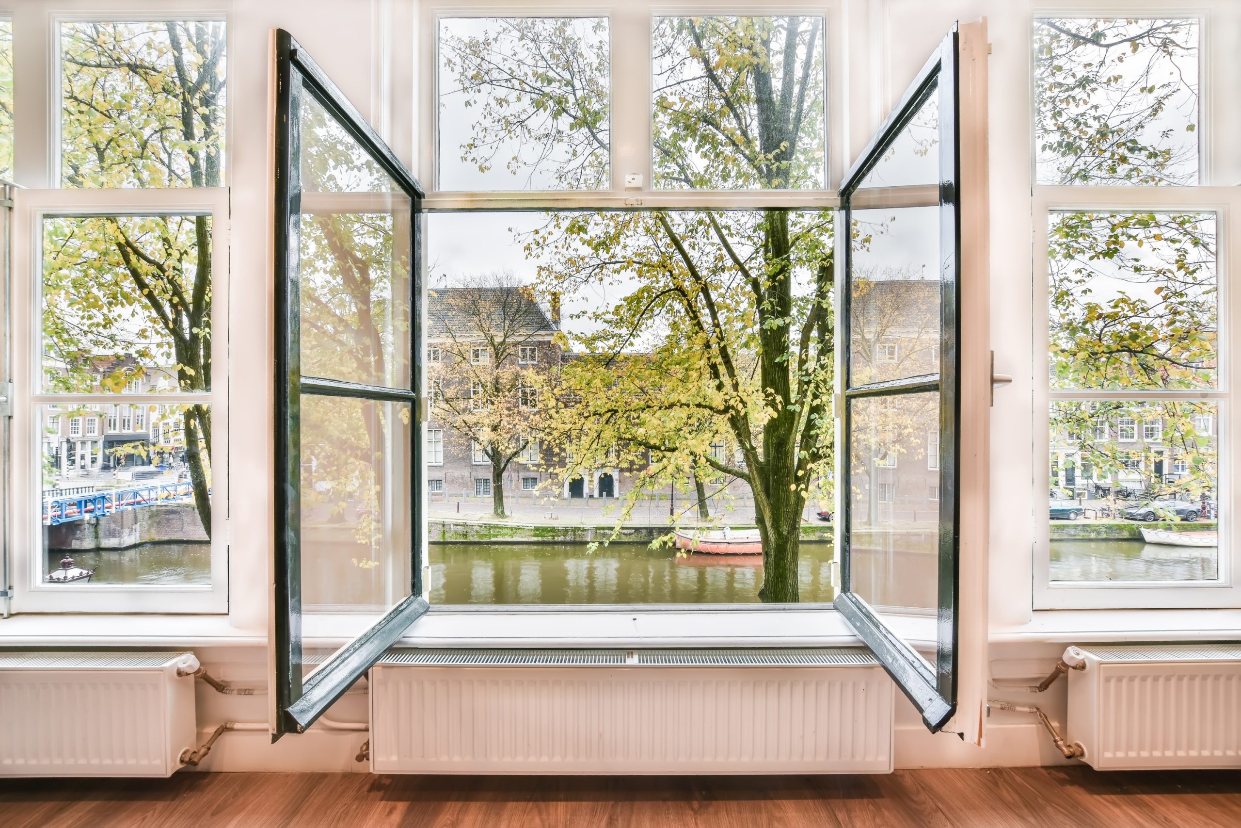 Open double-glazed window with scenic canal view showcasing thermal break window frame